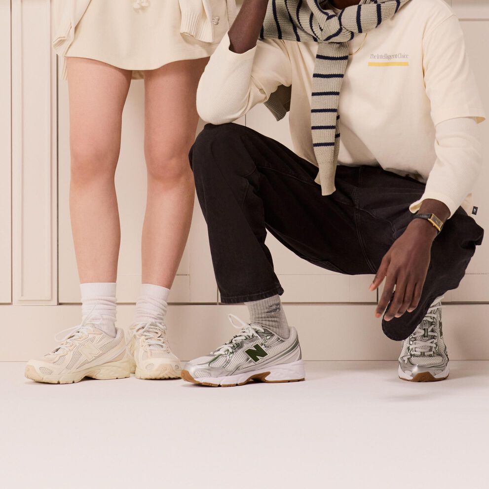 Young couple in front of white bookshelf wearing with and grey shoes. 